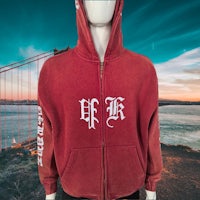 a mannequin wearing a red hoodie with a golden gate bridge in the background